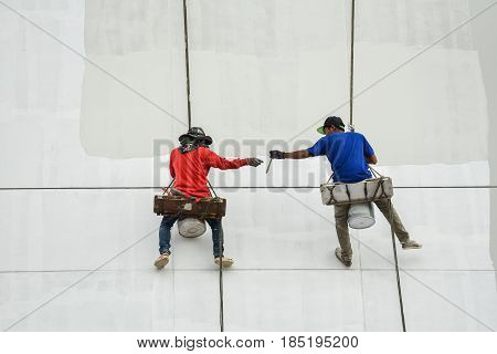Un safety Painters and harnesses hanging high building in construction sitehand brush color work concept