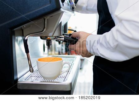 Barista use coffee machine for making coffee with white coffee cup.