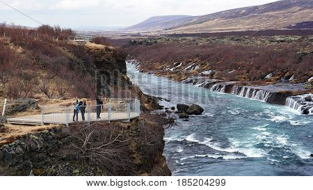 Happy Asian Family Travelers At Hraunfossar Waterfall In Iceland