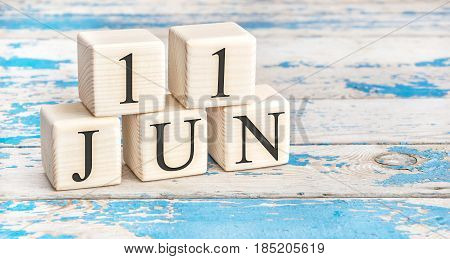 June 11th. Wooden cubes with date of 11 June on old blue wooden background.
