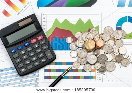 Calculator pen and coins on the graphs. Top view.