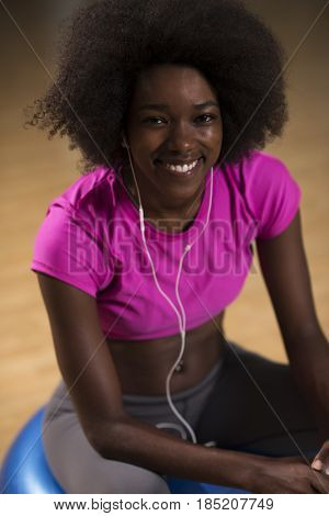 happy african american woman with a curly afro hairstyle in a  gym relaxing after pilates workout