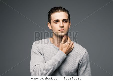 Portrait Of A Smart Serious Handsome Young Man Standing Against Grey Background