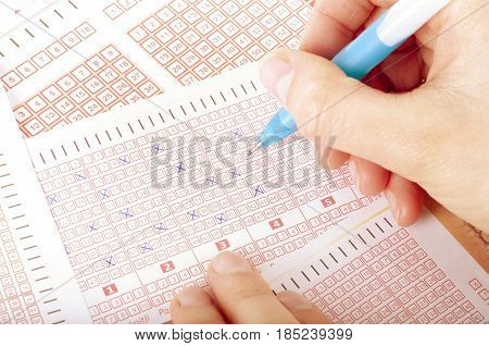 Person's Hand Marking Number On Lottery Ticket With Pen