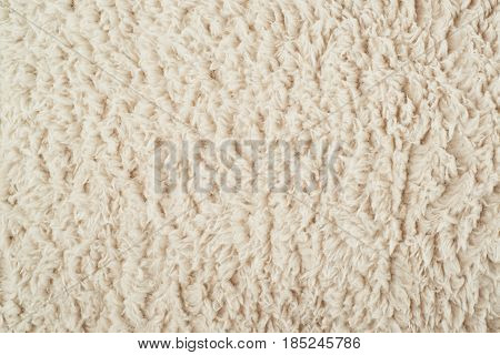 Close-up fragment of a beige colored artificial fur texture as a backdrop composition