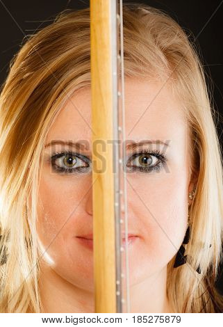 Music singing concept. Blonde musically talented woman holding electric guitar on black background