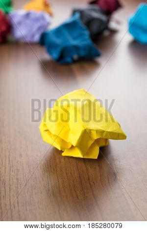 Yellow Crumpled Paper Ball On Dark Brown Wood Table With Group Of Colorful Crumpled Paper Ball At Ba