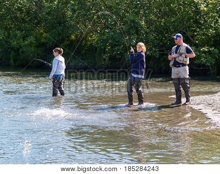 Alaska, USA - August 11, 2008; Alaskan salmon fishing. Two young women and a man guide salmon fishing in small river in Alaska.