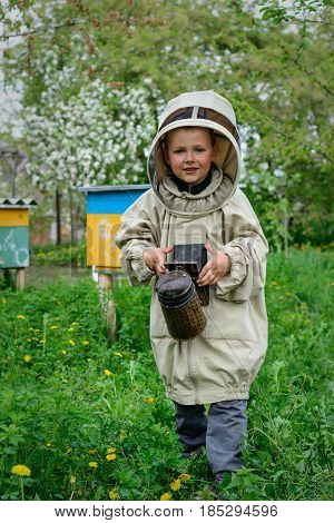 The boy in protective clothing beekeeper works on an apiary. Apiculture