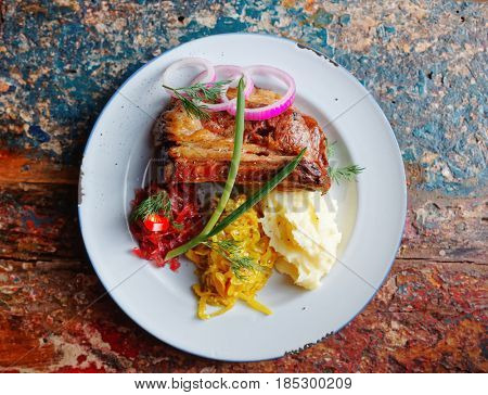Grilled pork ribs with sauerkraut and mash potatoes on grunge peeled paint surface, toned image