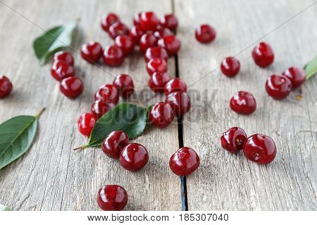 ripe cherries scattered on a wooden background there are cherry leaves top view