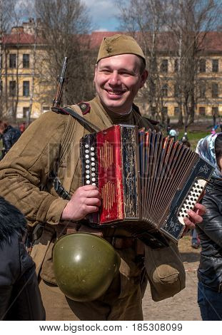 Gatchina Russia - May 7 2017: Historical reconstruction of the battles of World War II. A Soviet soldier plays the accordion and sings funny songs.
