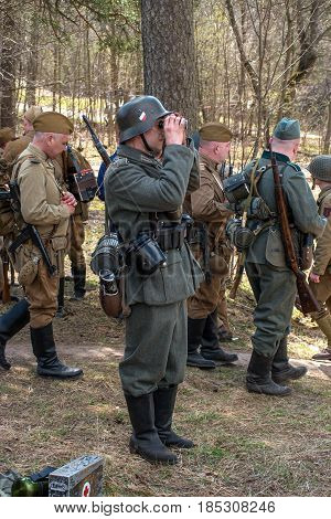 Gatchina, Russia - May 7, 2017: Historical reconstruction of the battles of World War II. Soviet and German soldiers before the battle. A German soldier looks through binoculars.