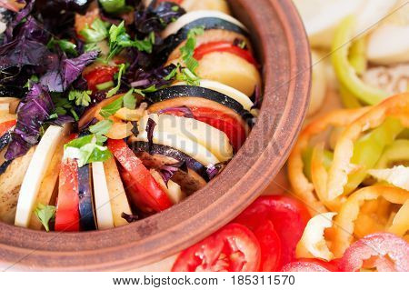A dish of vegetables in a pottery. Stew of tomatoes, peppers, eggplant with basil and parsley. Menu of Italian cuisine