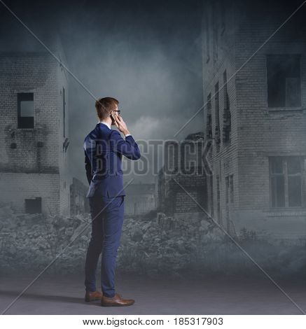 Businessman talking on a mobile phone. Apocalyptic background. Crisis, default, setback concept.