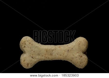 Dog biscuit on black background to connote a concept of feeding animals