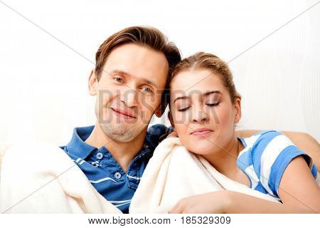 Smiling loving couple sitting on couch with blanket