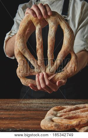 Baker's hands hold fougas bread