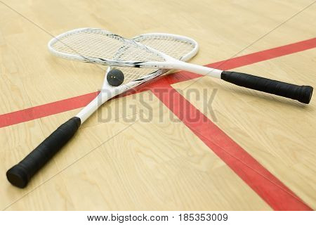 crossed squash rackets and ball on the wooden floor. Racquetball equipment on the court near red line. Photo with selective focus