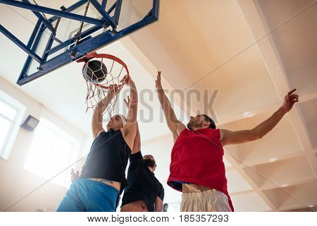 Low angle shot of basketball players playing basketball on the court.