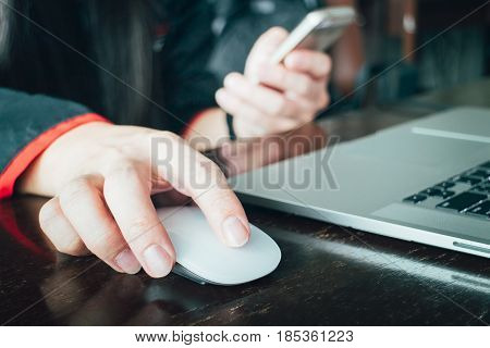 Close up, Hand using Mouse and Computer Laptop on wooden table.