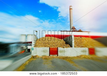 Blurred Bio Power Plant With Storage Of Wooden Fuel (biomass) Against Blue Sky