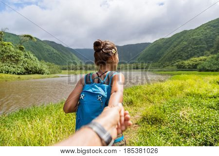Hawaii travel nature hiker follow me woman hiking in Pololu valley holding hand of boyfriend following leading girlfriend walking. Big island destination, woman tourist in Hawaii, USA.