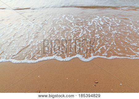 Soft white wave of sea on sandy beach used as Background.