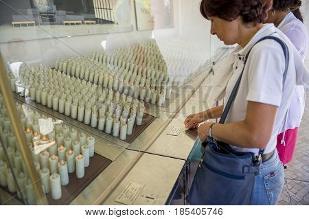 Fatima Portugal - May 13 2014: Woman lighting a candle to pay a promise at the Sanctuary of Fatima during the celebrations of the apparition of the Virgin Mary in Fatima Portugal.
