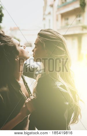 Two sexy women or sexi girls with beautiful long hair hugging on sunny day outdoors on urban background. Lesbian couple. Love and desire