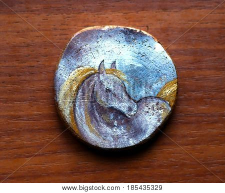 Round blue paitned picture on a piece of wood. Beautiful blue grey horse with blonde yellow mane