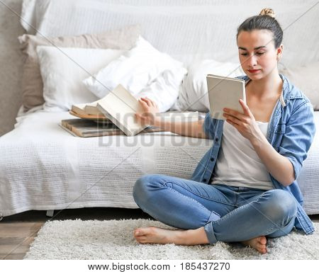 girl reading a book in a cozy room on the couch with a Cup of tea , the concept of leisure, and comfort