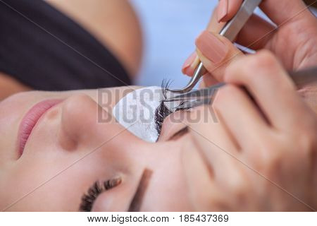 Makeup Master Corrects, And Strengthens Eyelashes Beams, Holding Out A Pair Of Tweezers In A Beauty