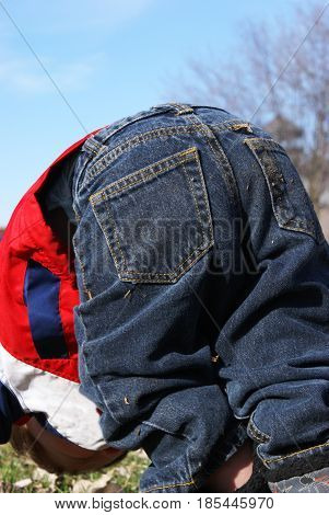 A young toddler does summersaults outside in the park.