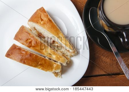 Fresh homemade apple pie and tea with milk on a wooden background