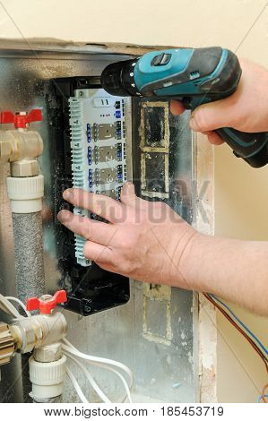 Man's hands fixing a switch for thermostats and servo drives valves in a home heating system.