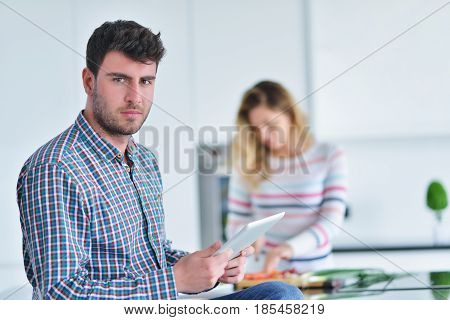 Couple standing and sitting at the kitchen while smiling and man reading a newspaper and holding mug before work