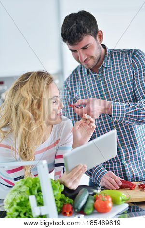 Couple in home kitchen using electronic tablet.