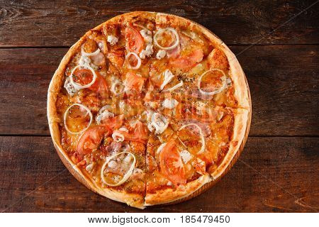 Junk food, unhealthy eating, bad habits, calories. Hot fresh baked pizza with ham, onion, tomato and cheese served on dark wooden table, flat lay.