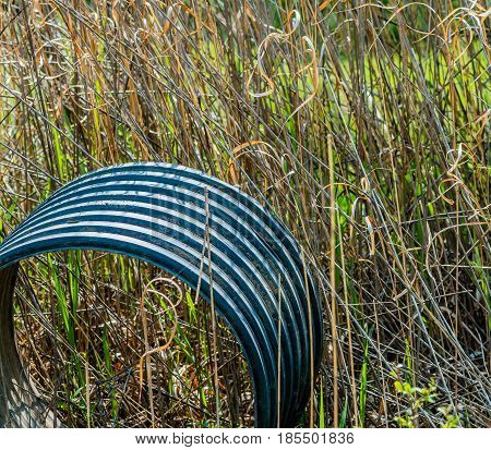 Large industrial plumbing section left laying in tall grass in a woodland area in South Korea.