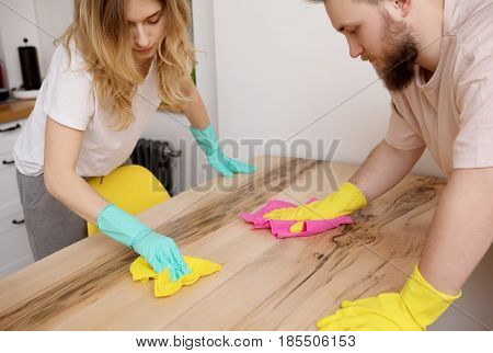 Young couple cleaning table in kitchen, in home.