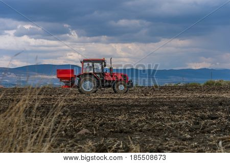 Tractor spreading artificial fertilizers in spring days