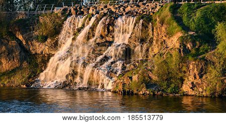 Beautiful waterfall at sunset in the rays of the setting sun. Dnepropetrovsk Ukraine
