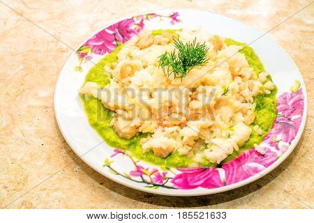 Plate with prawns and shrimps risotto on spinach bed