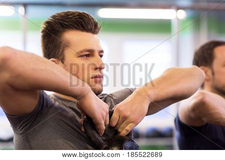 sport, fitness, weightlifting and people concept - close up of man with kettlebell exercising at group training in gym