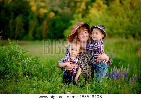 Sister hugging two younger brothers, summer day
