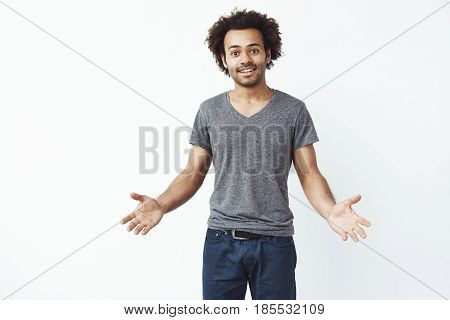 Stylish and handsome african man with arms wide open against white wall inviting to a gig. Copy space.