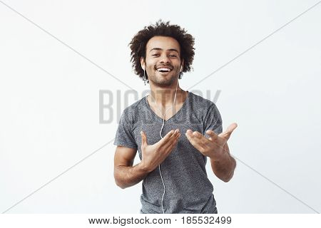 Cheerful african man listening to music in headphones dancing singing. White background.