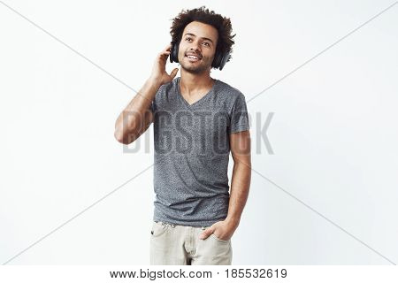 Young african man in headphones listening to music over white background. Copy space.