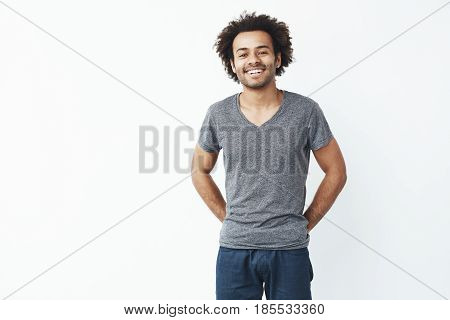 Young handsome african man smiling looking at camera over white background. Copy space.